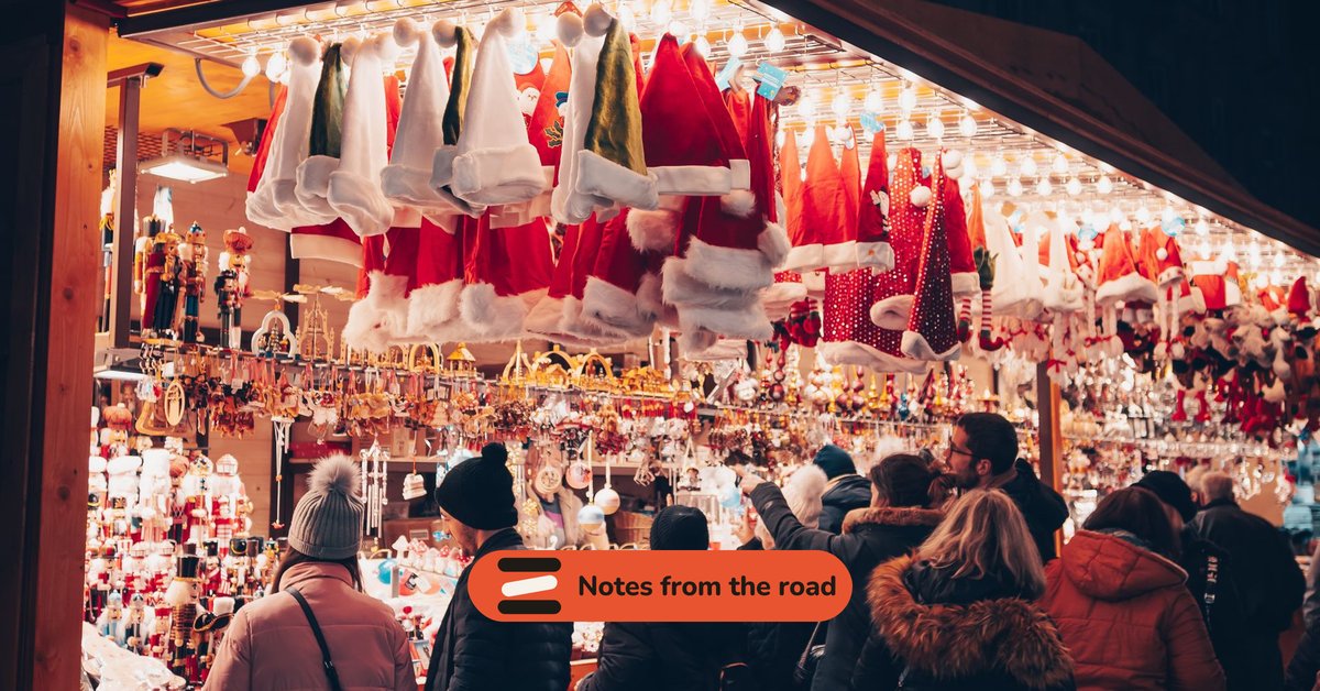 A Christmas market stall at night with customers at the counter